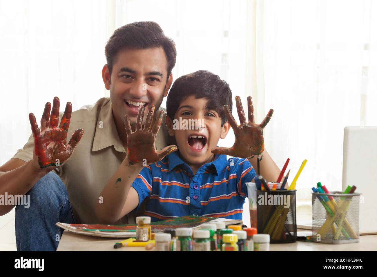 Smiling father and son finger painting together Stock Photo