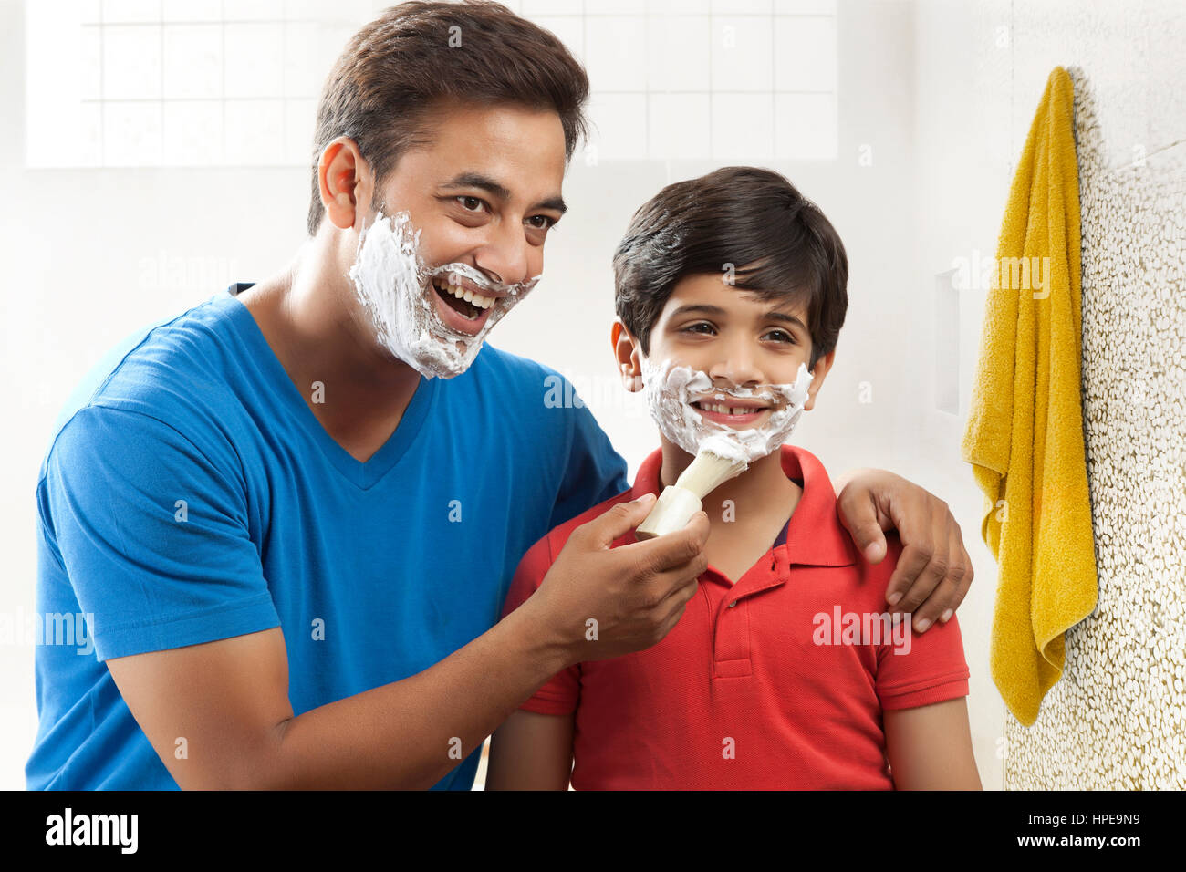 Man applying shaving cream lather on face of his son Stock Photo Alamy