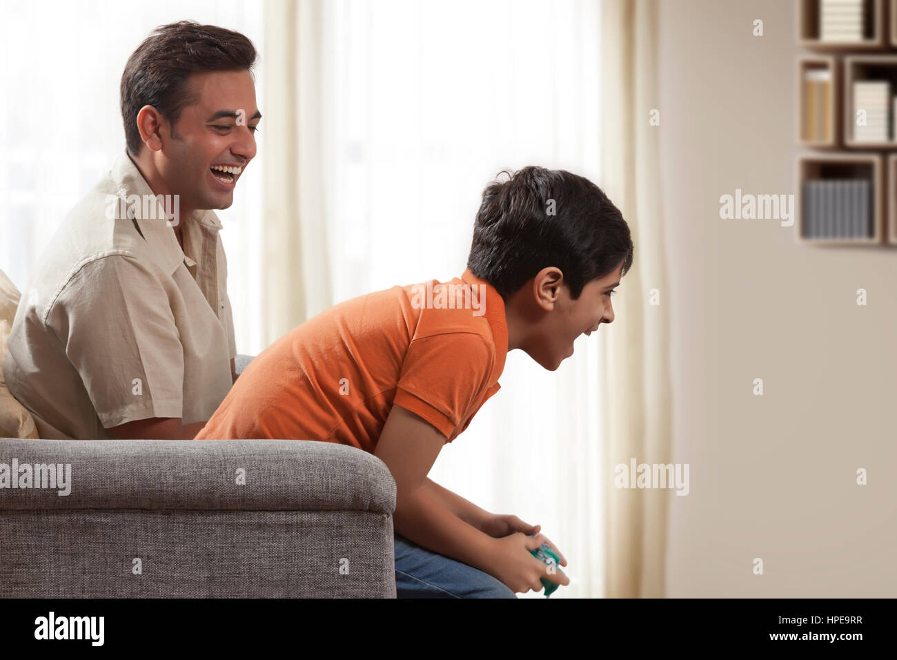 Father playing video game with boy sitting on his shoulder Stock Photo
