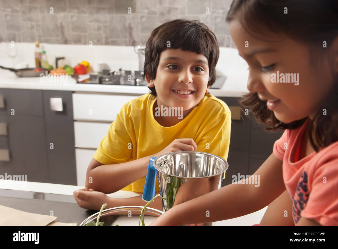 Two kids having fun together in kitchen Stock Photo