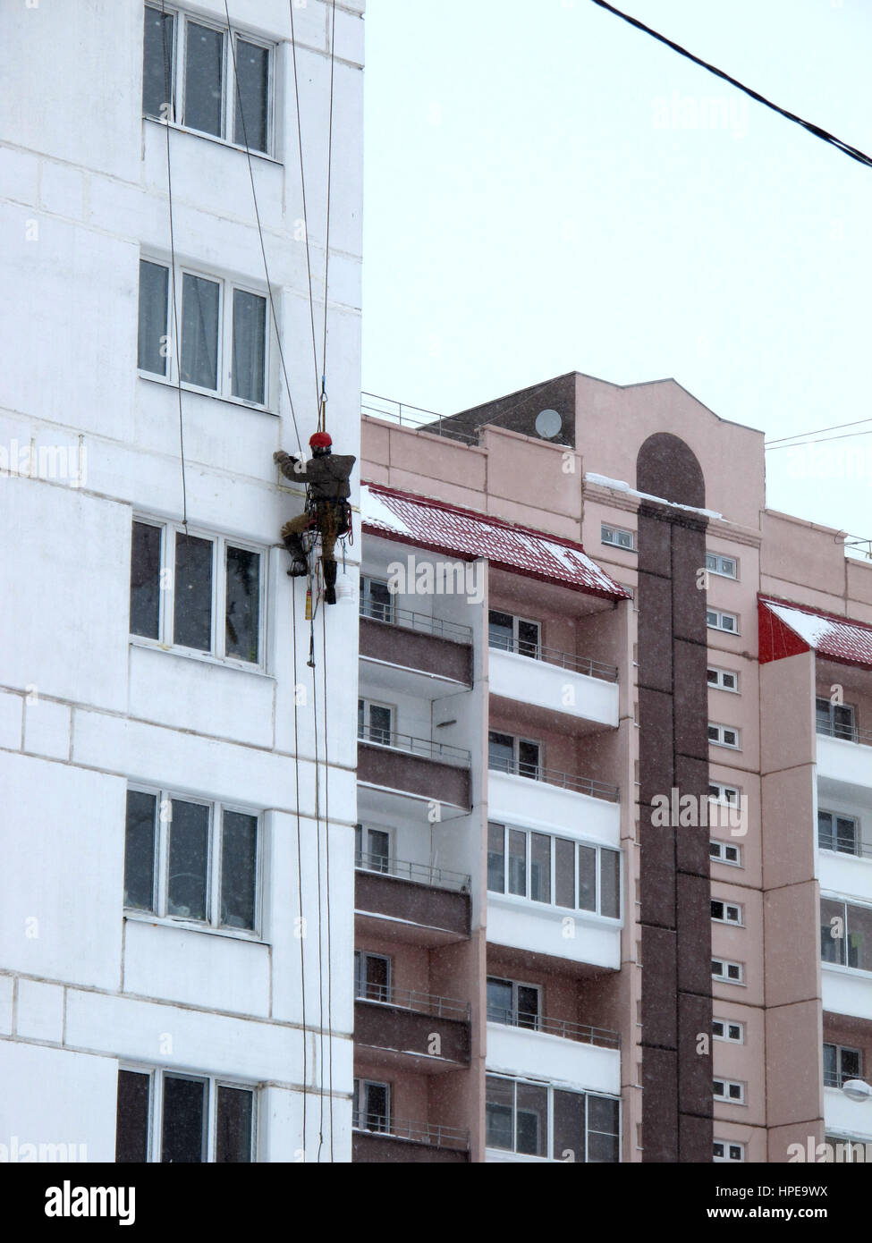 Industrial climber in helmet and uniform puttying wall on height. Risky job. Extreme work. Worker alpinist. Stock Photo