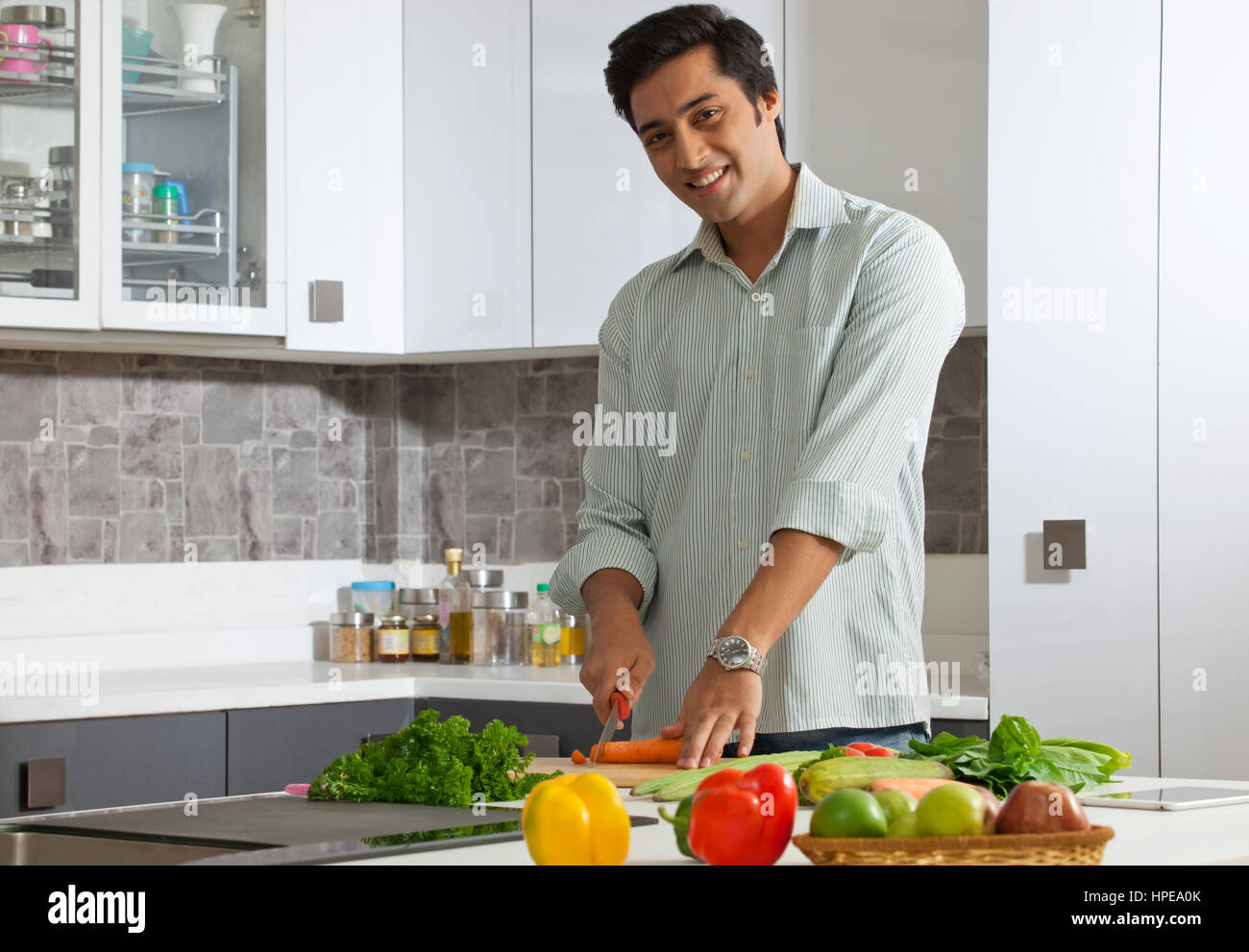 Man cutting carrot in domestic kitchen Stock Photo