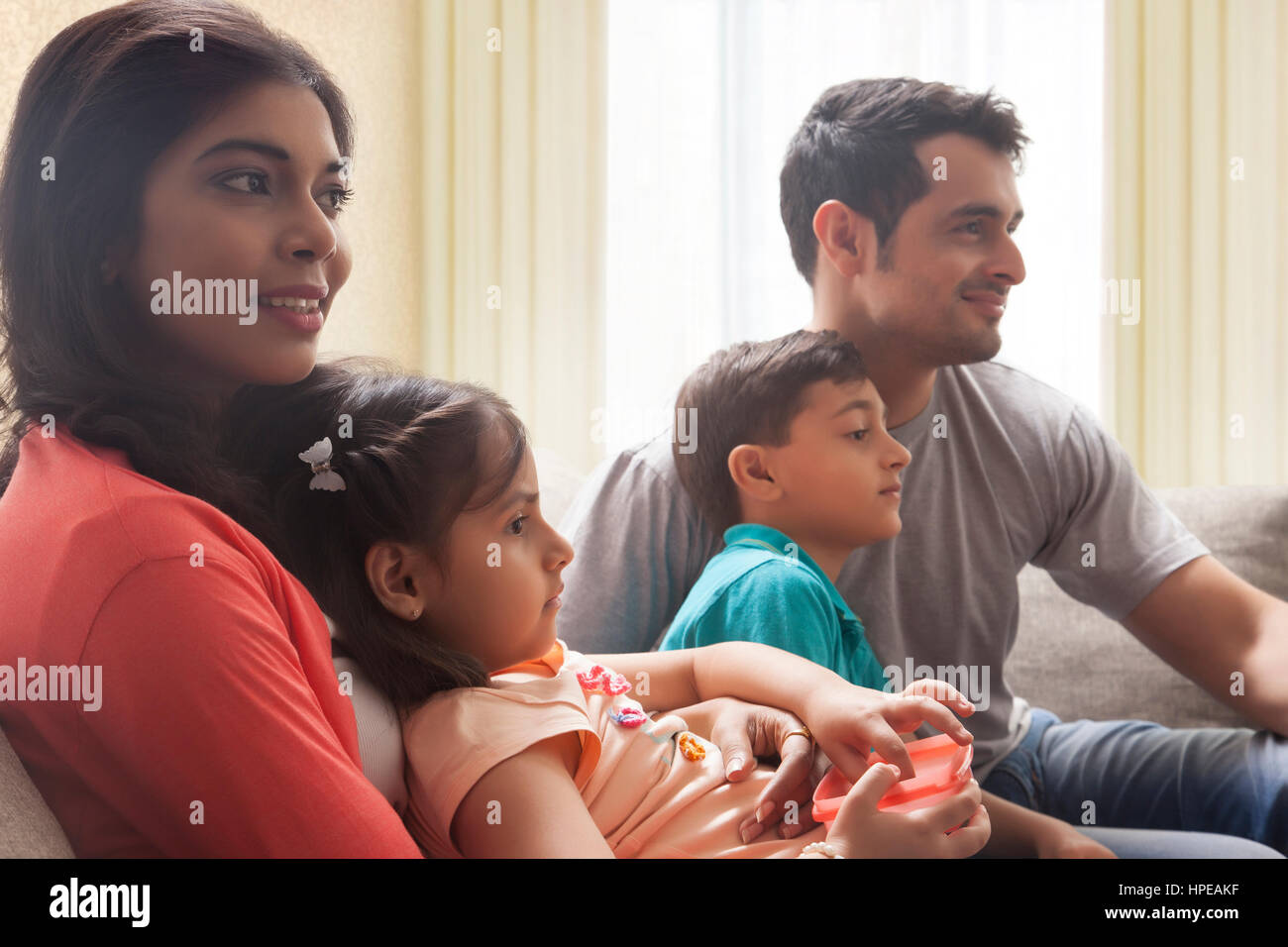 Family with son and daughter sitting on sofa and watching TV Stock Photo