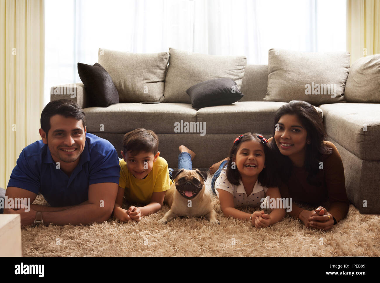 Happy family with pug posing on carpet in living room Stock Photo