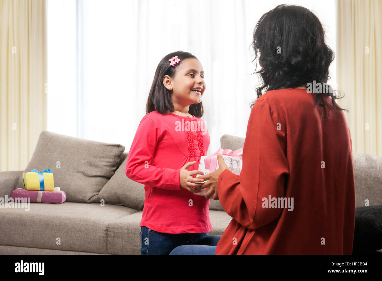 Rear view of mother presenting gift to daughter Stock Photo