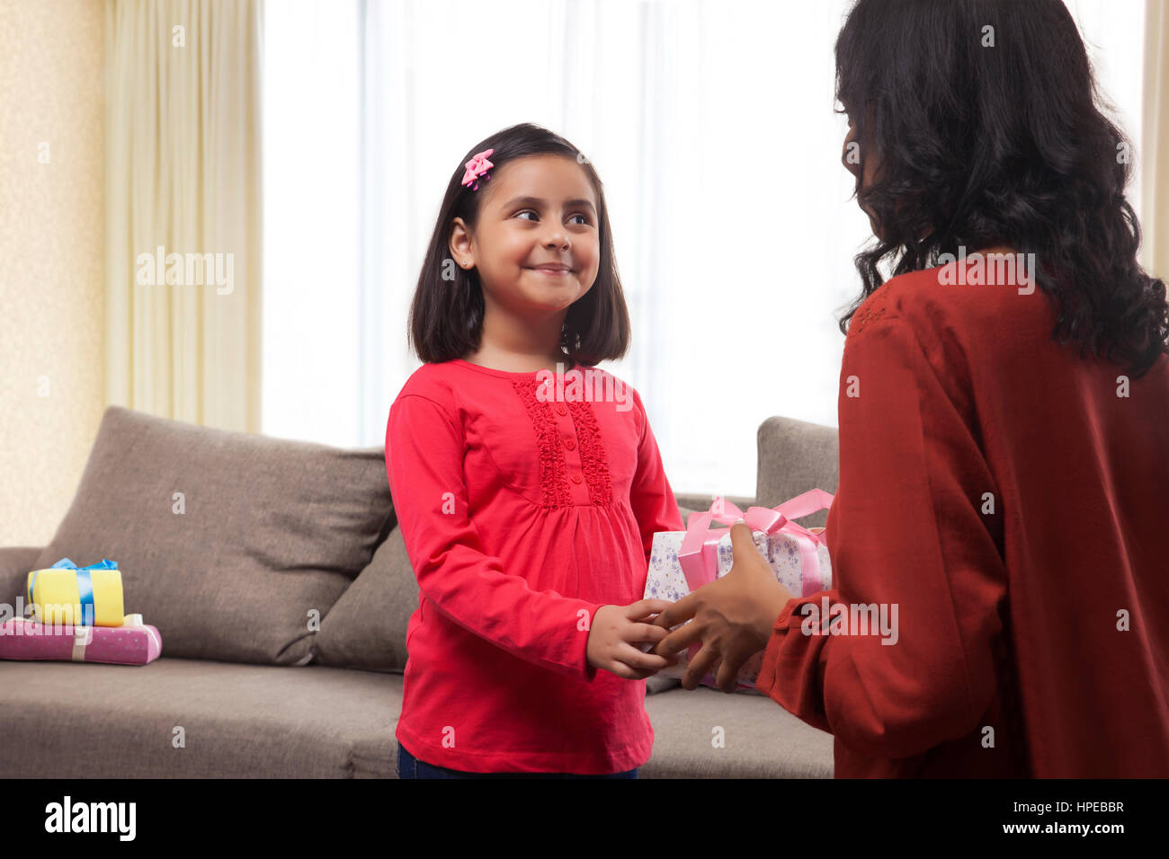Rear view of mother presenting gift to daughter Stock Photo