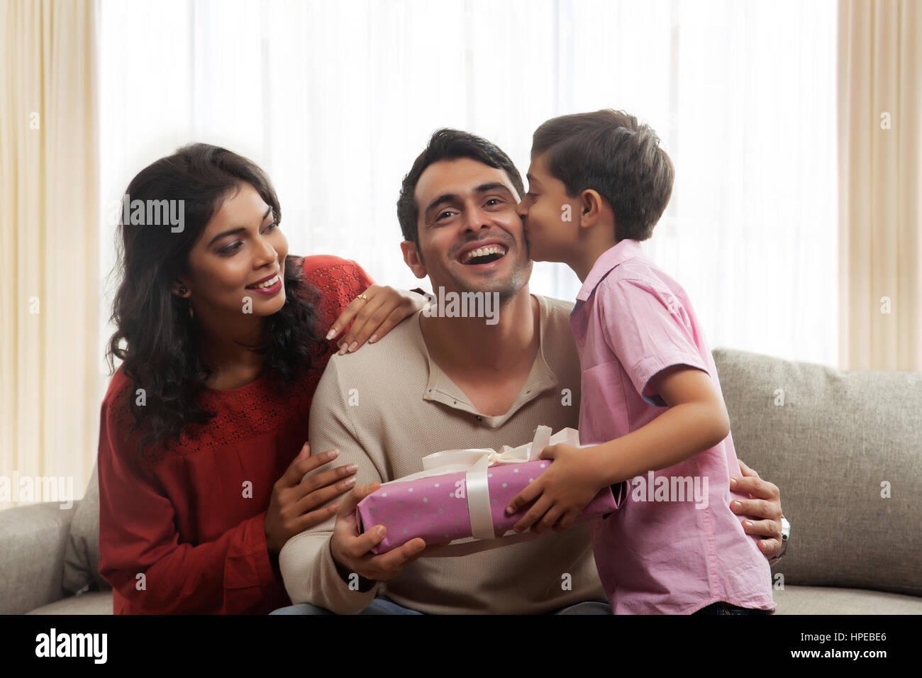 Son kissing father and giving gift while mother looking at them Stock ...