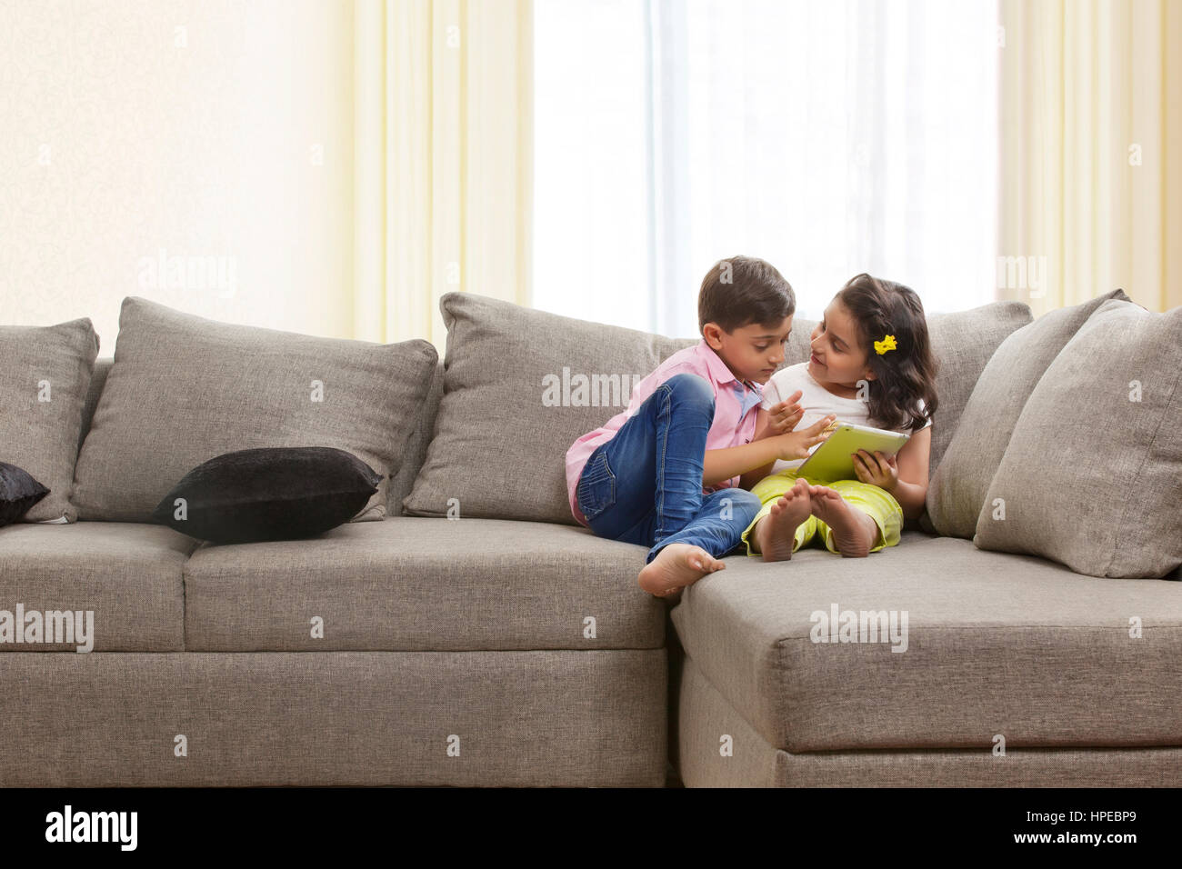 Brother and sister sitting on sofa using digital tablet Stock Photo - Alamy