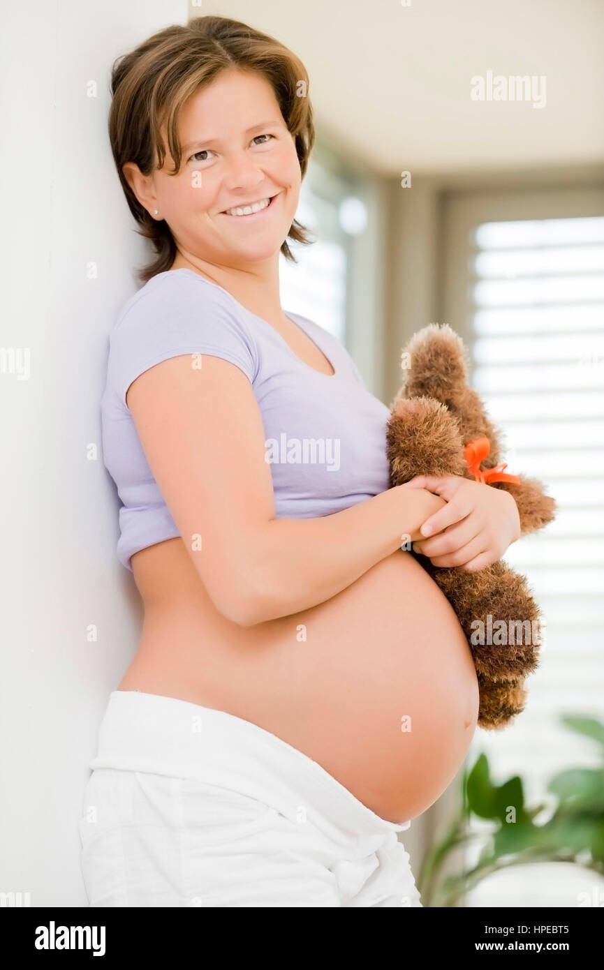 Model released , Schwangere Frau mit Teddybaer in der Hand - pregnant woman with teddy bear Stock Photo