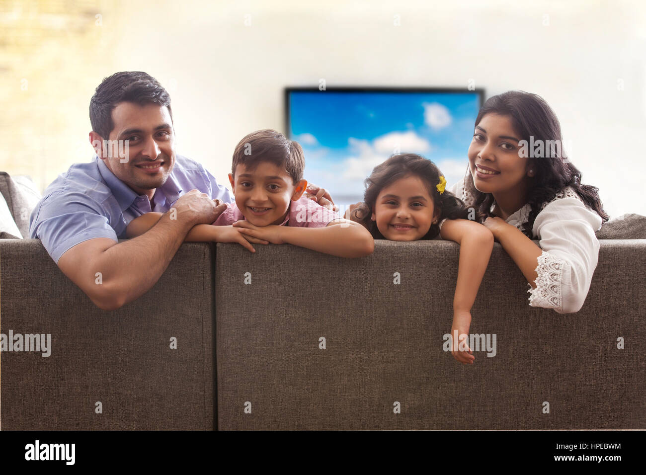 Portrait of family sitting on sofa in living room Stock Photo - Alamy