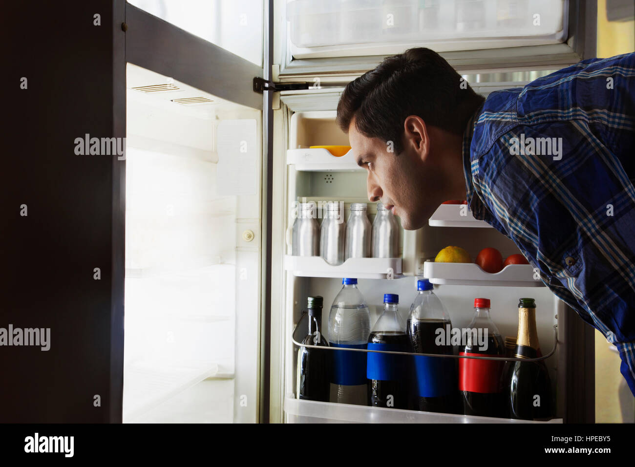 Young man searching food in the fridge at night Stock Photo