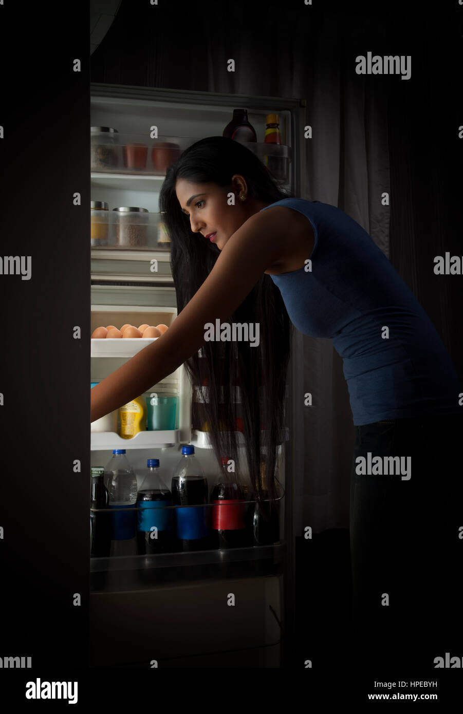 Young woman searching food in the fridge at night Stock Photo