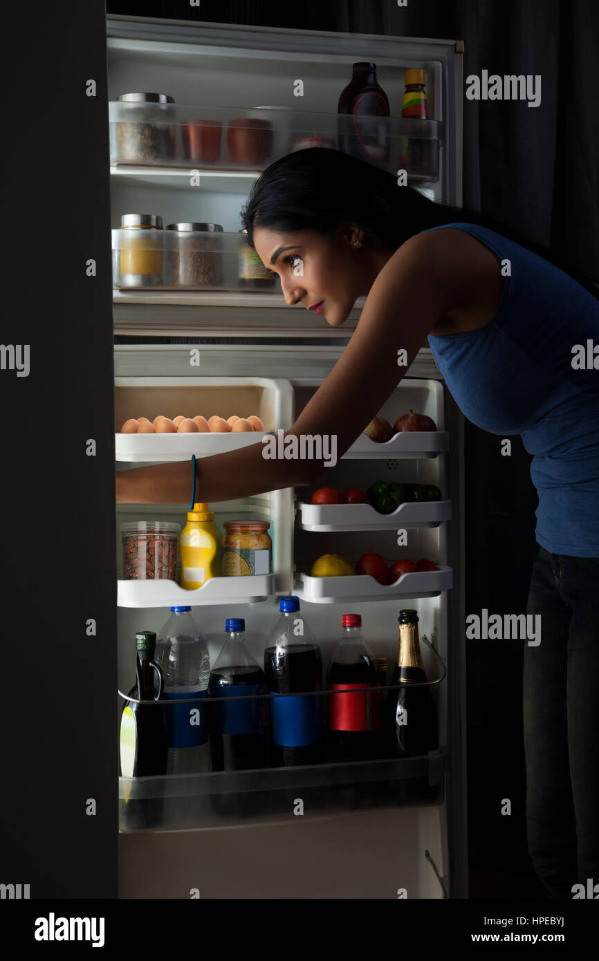 Young woman looking in the fridge at night Stock Photo