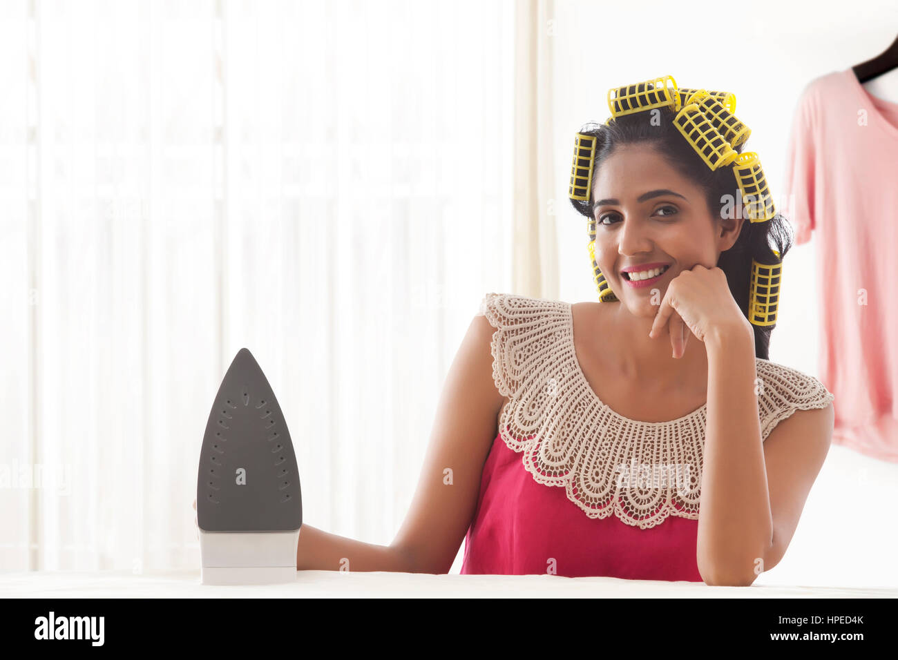 Young woman with hair curlers holding iron appliance Stock Photo