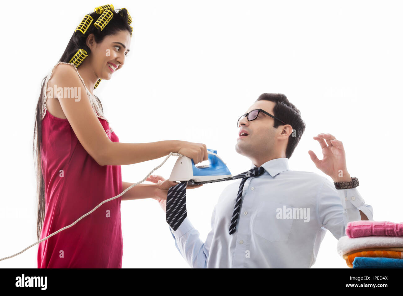 Young woman with curlers ironing man's tie Stock Photo