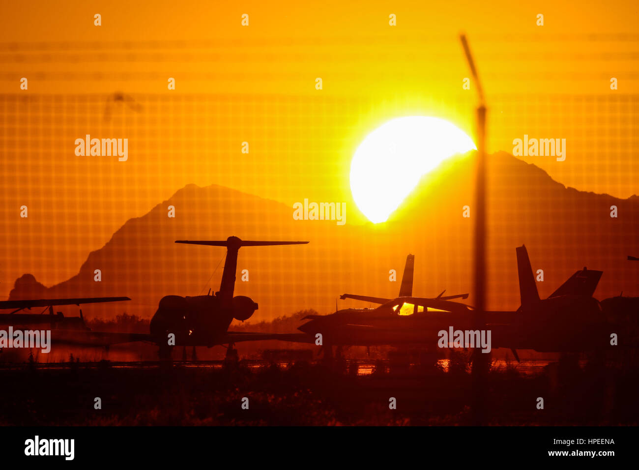 Bright sun and intense orange and gold color. You can see an impressive solar circle at sunset with the planes at the airport Stock Photo