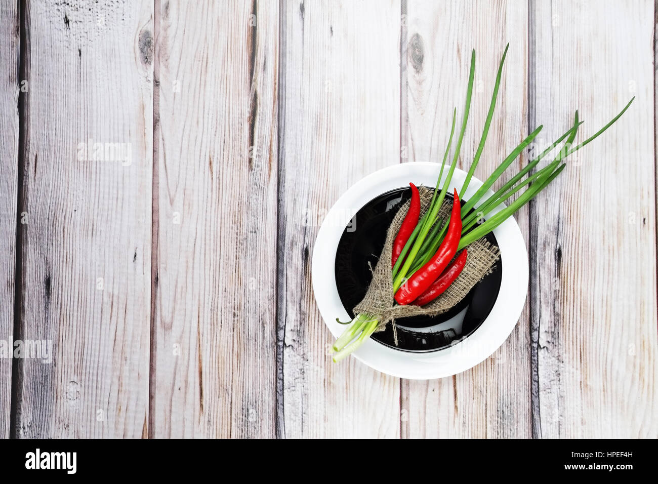 Red hot chilli pepper and scallions on black plate wooden background Stock Photo