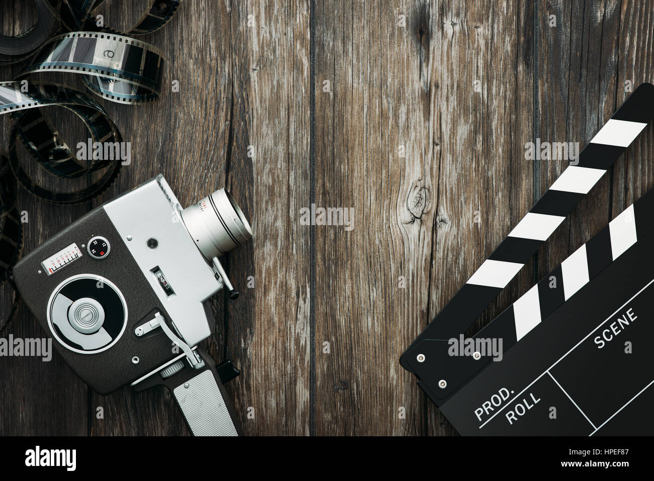 Vintage film camera, filmstrip and clapper board on a wooden desktop
