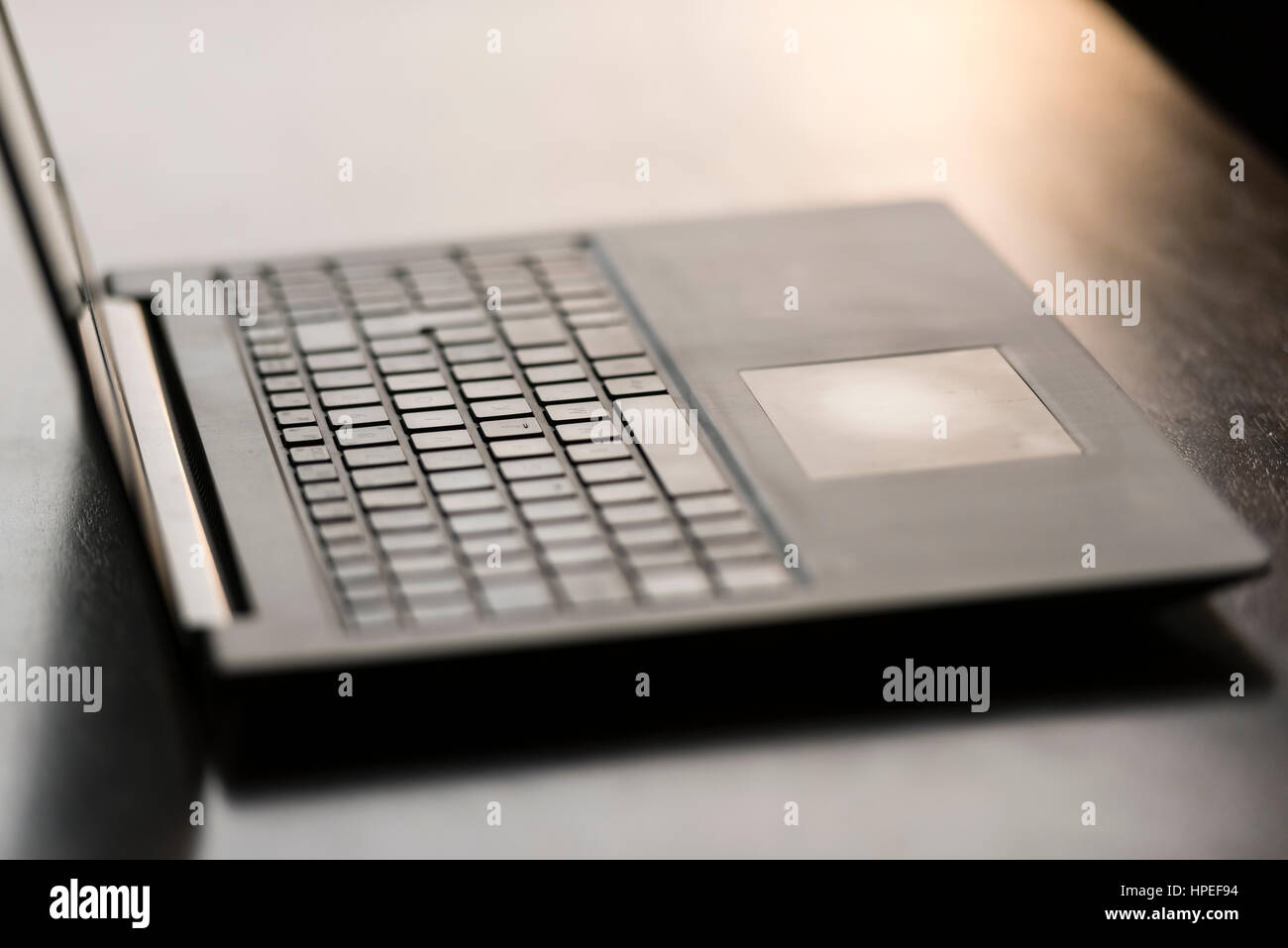 Opened laptop computer on a wooden desk. Focus on touchpad, backlight, no people Stock Photo