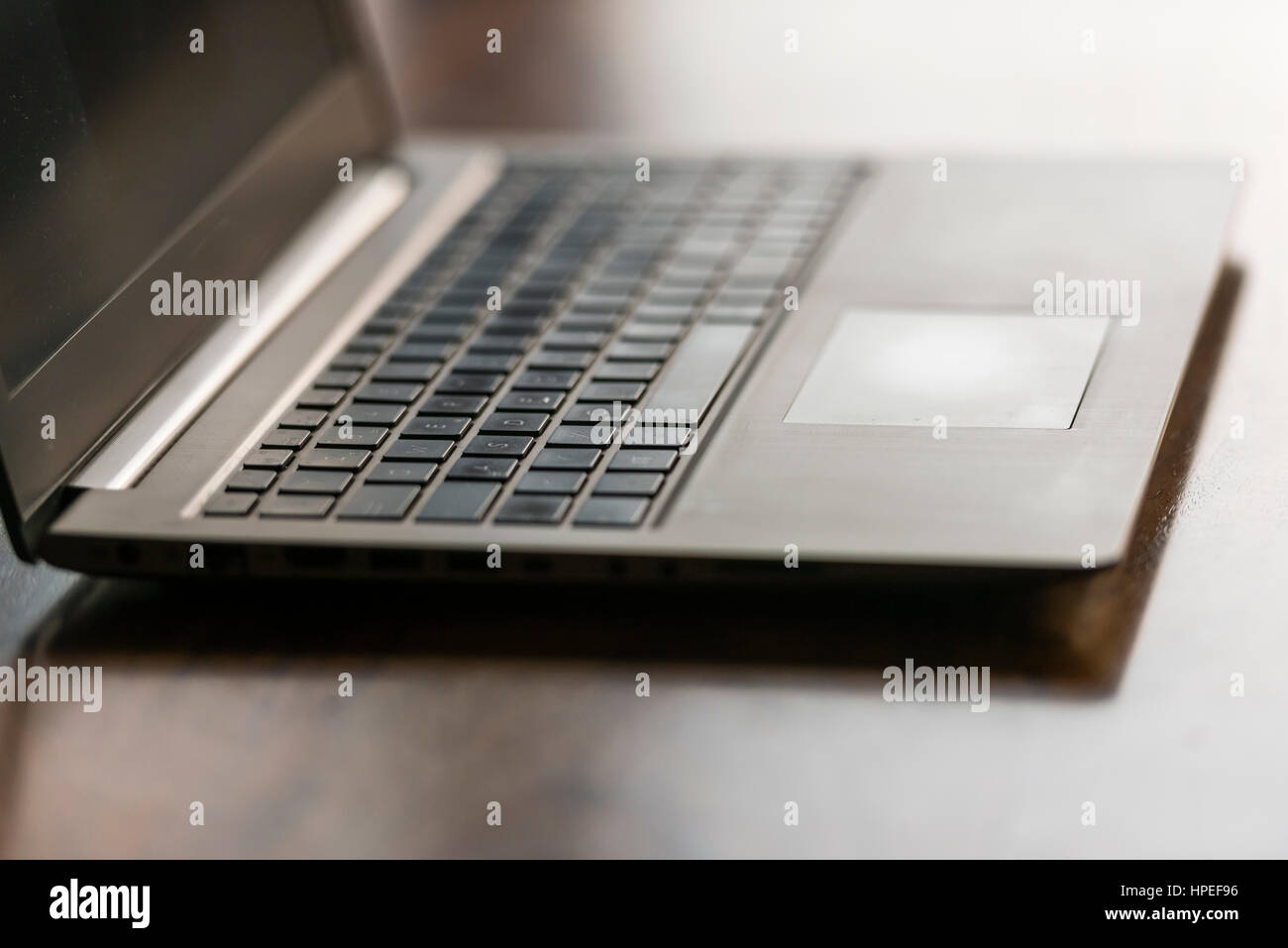 Opened laptop computer on a wooden desk. Focus on touchpad, backlight, no people Stock Photo