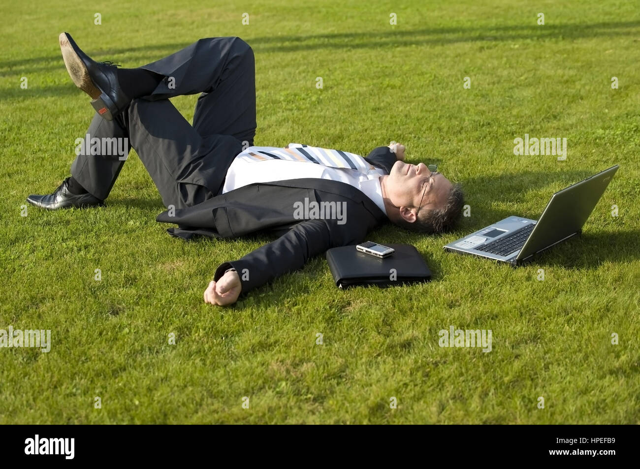 Model released , Geschaeftsmann rastet in der Wiese - businessman relaxing in meadow Stock Photo