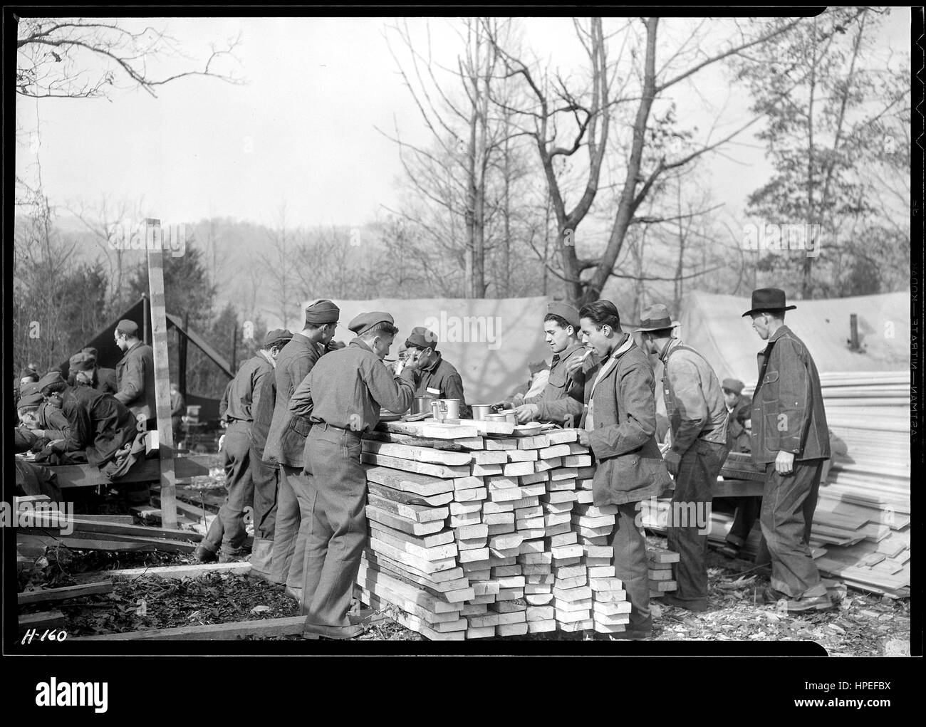 Photograph of young men that were part of the Civilian Conservation Corps eating lunch at their camp, Tennessee, November 17, 1933. Image courtesy Lewis Wickes Hine/US National Archives. Stock Photo