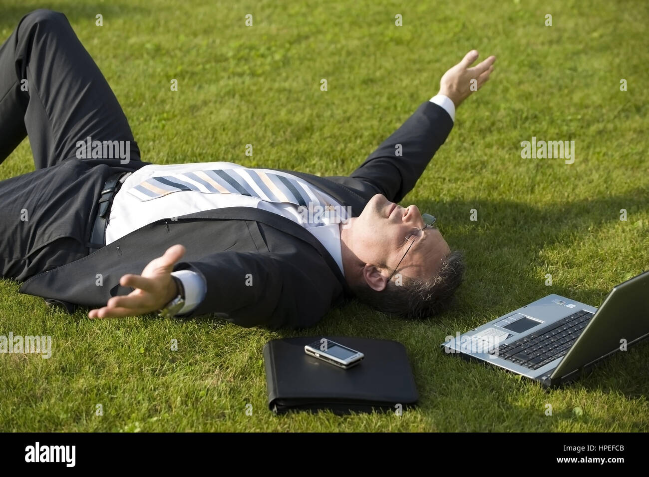 Model released , Geschaeftsmann rastet in der Wiese - businessman relaxing in meadow Stock Photo