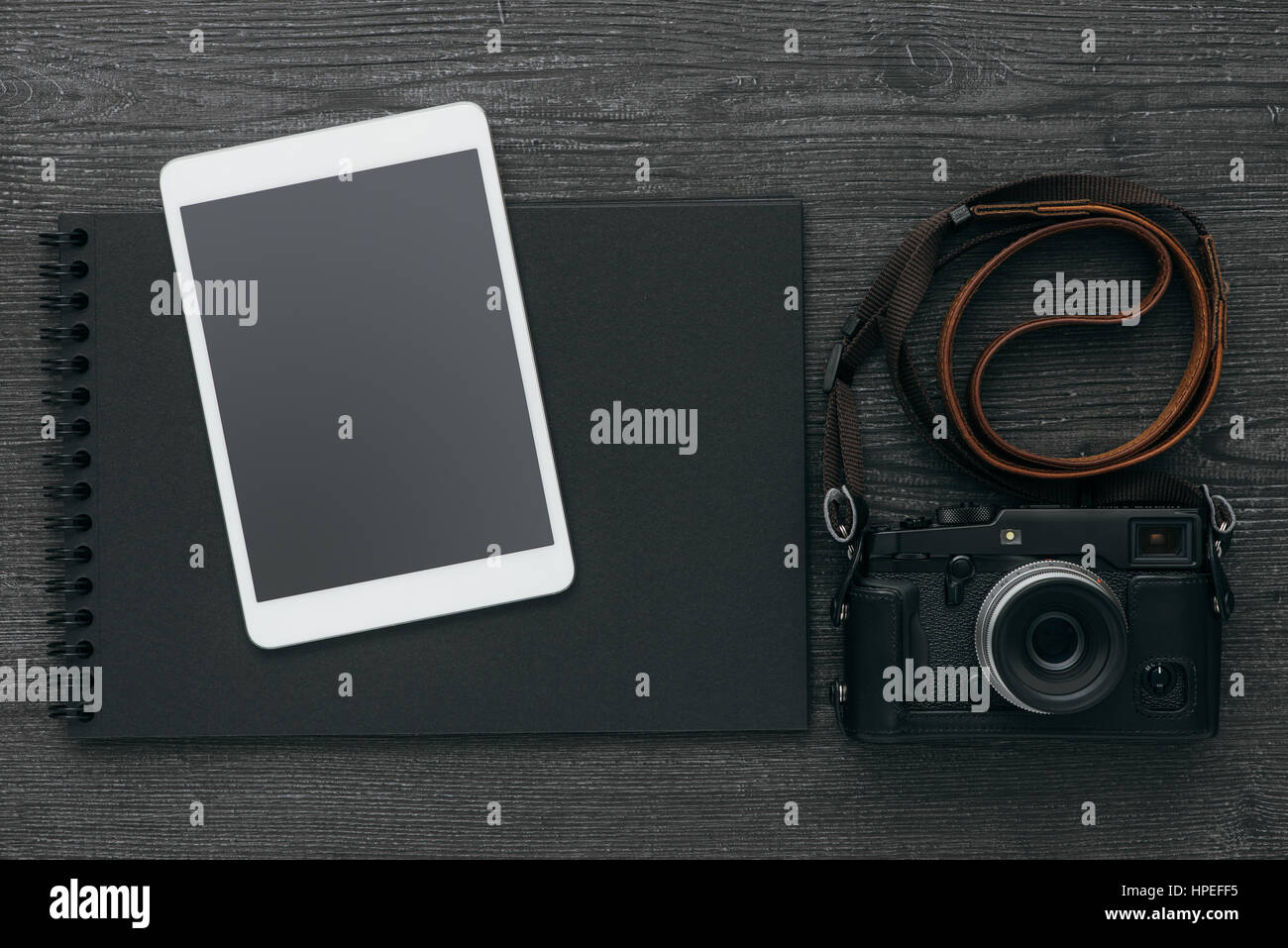 Blank dark photo album, professional camera and touch screen tablet