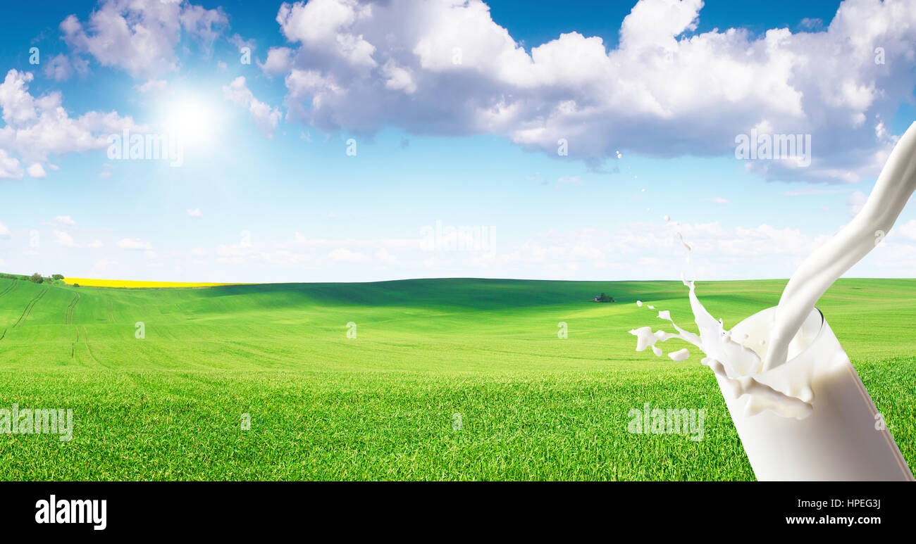 Milk flowing into glass on natural background Stock Photo