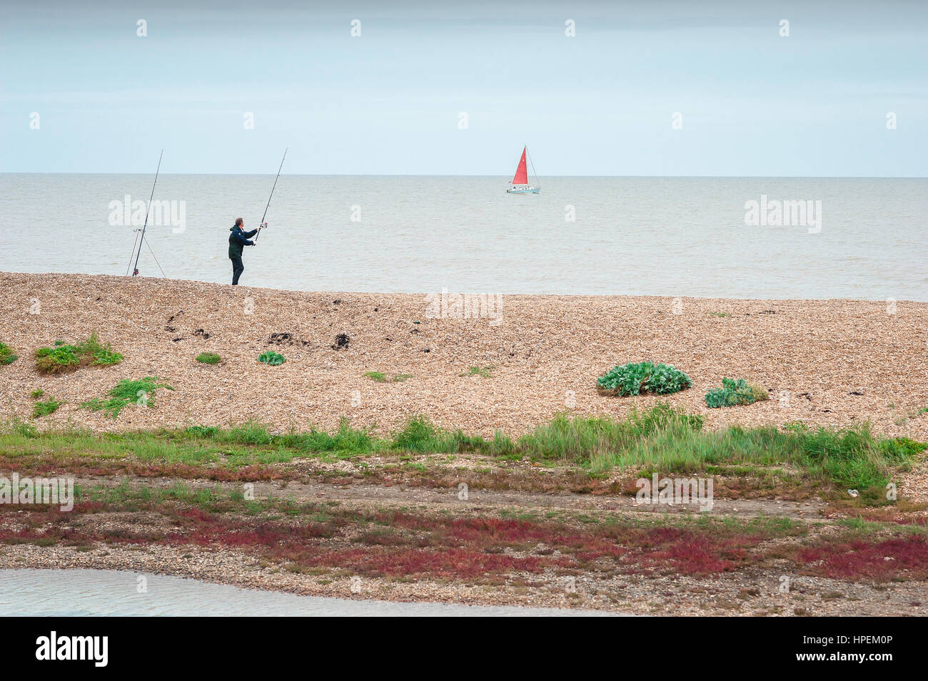 Suffolk coast UK, view of a man fishing alone on the beach at Bawdsey in Suffolk, UK. Stock Photo