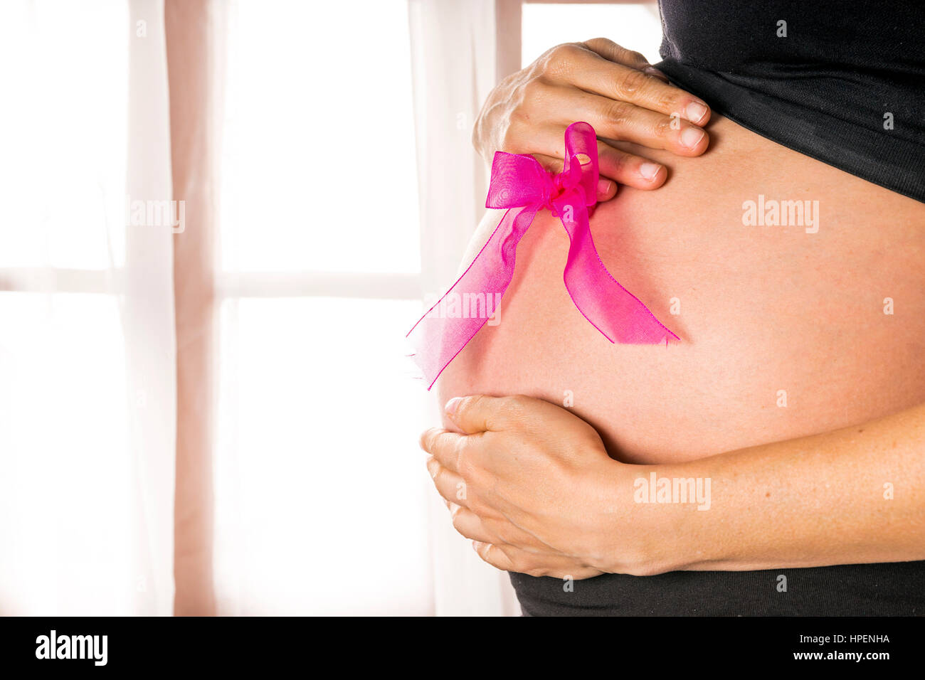 Mom holds pink ribbon on her belly Stock Photo