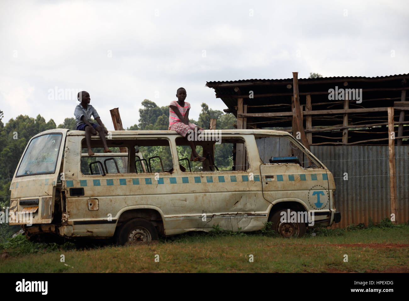 Two children sitting on a broken taxi bus (matatu) in Uganda Stock Photo