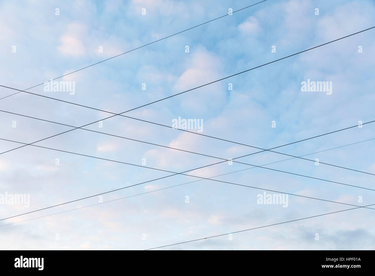 Intersecting power lines in front of cloudy background Stock Photo - Alamy