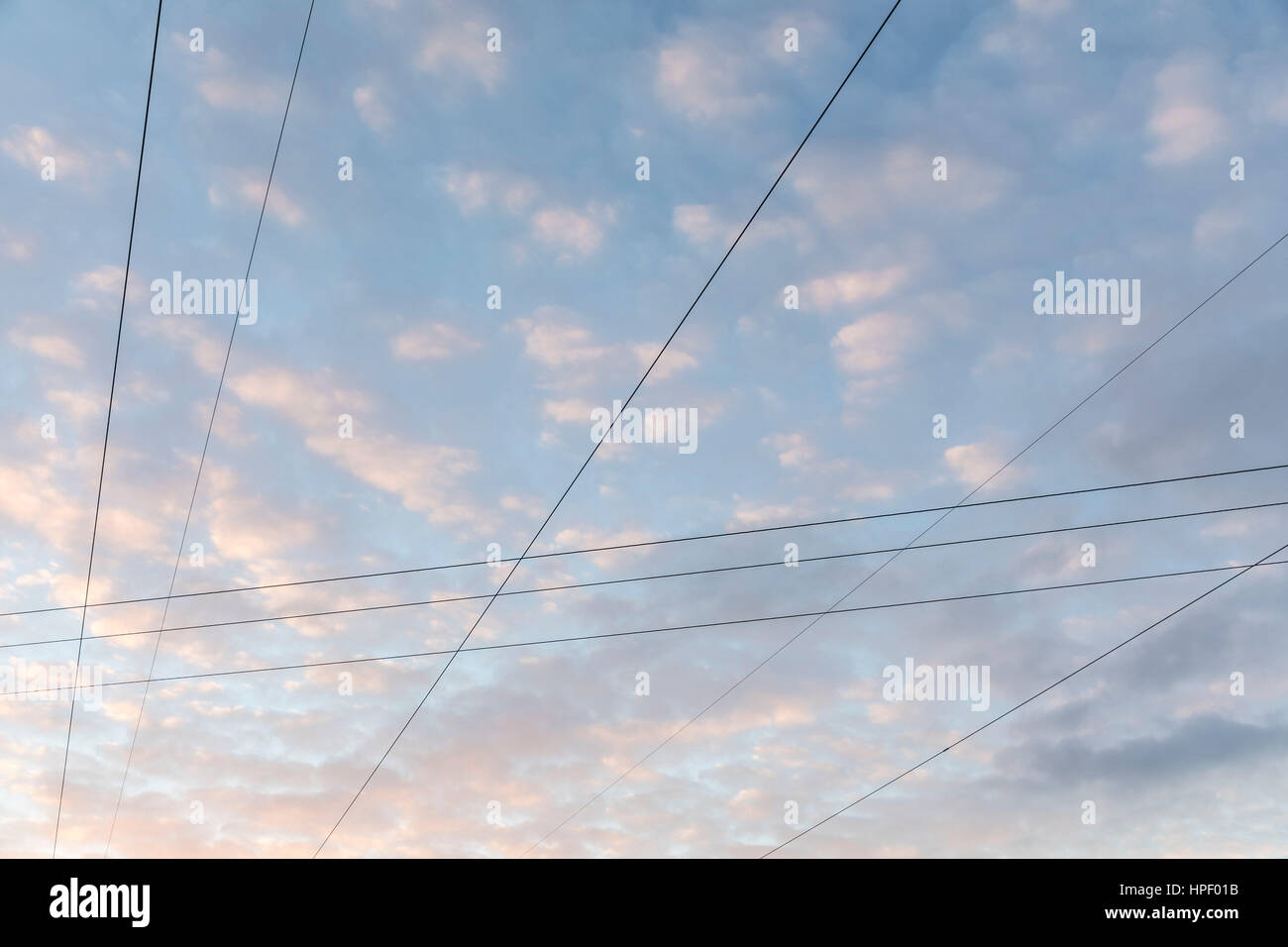 Intersecting power lines in front of cloudy background in the evening ...