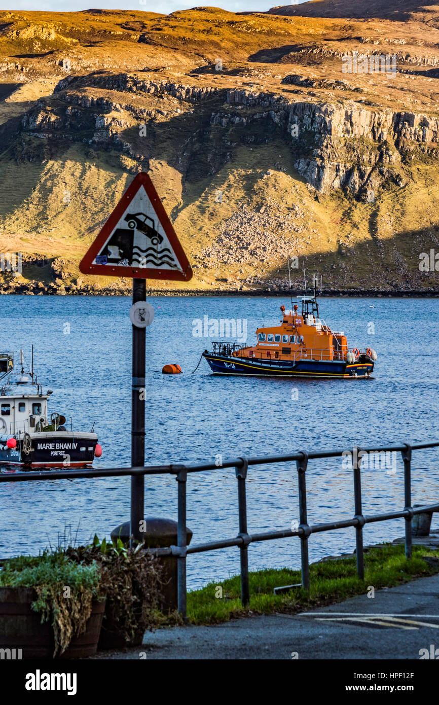 Portree lifeboat, RNLB Stanley Watson Barker, anchored in Portree Harbour, Isle of Scotland, with road sign in foreground and Ben Tianavaig behind. Stock Photo