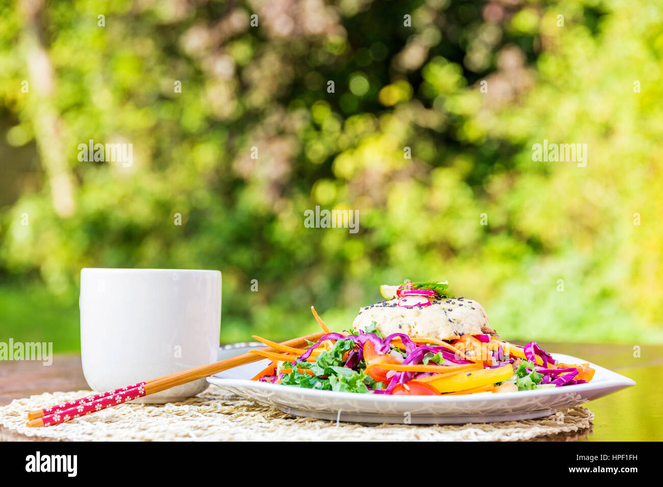 Asian vegetarian burger dish with salad and tea served in a green environment Stock Photo
