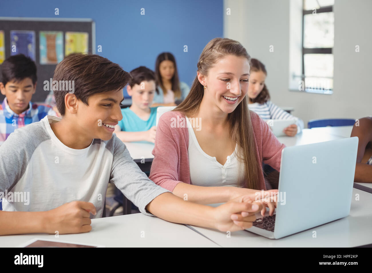 Students using digital tablet and laptop in classroom at school Stock