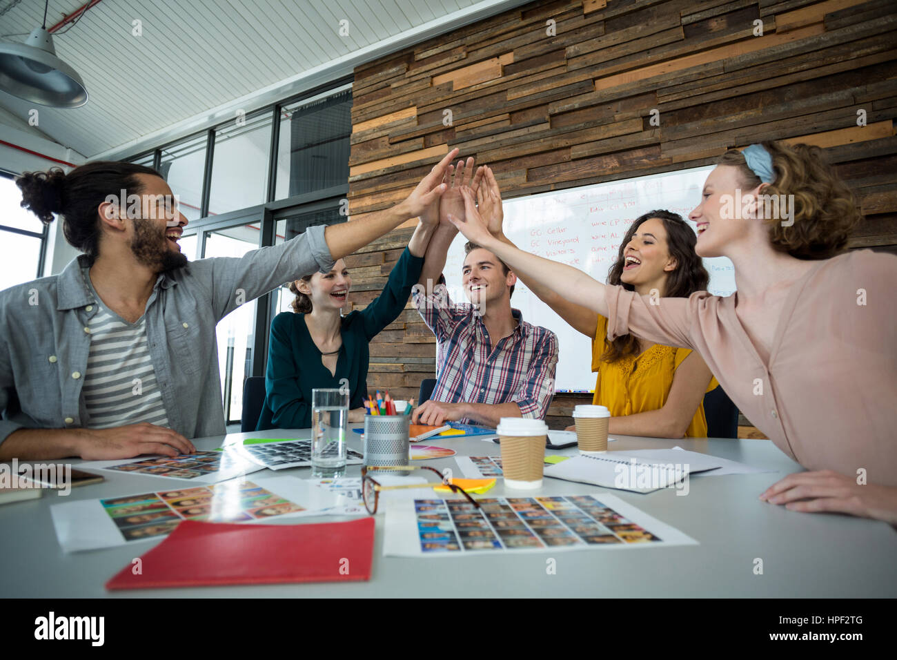 Happy graphic designers giving high five during meeting in office Stock ...