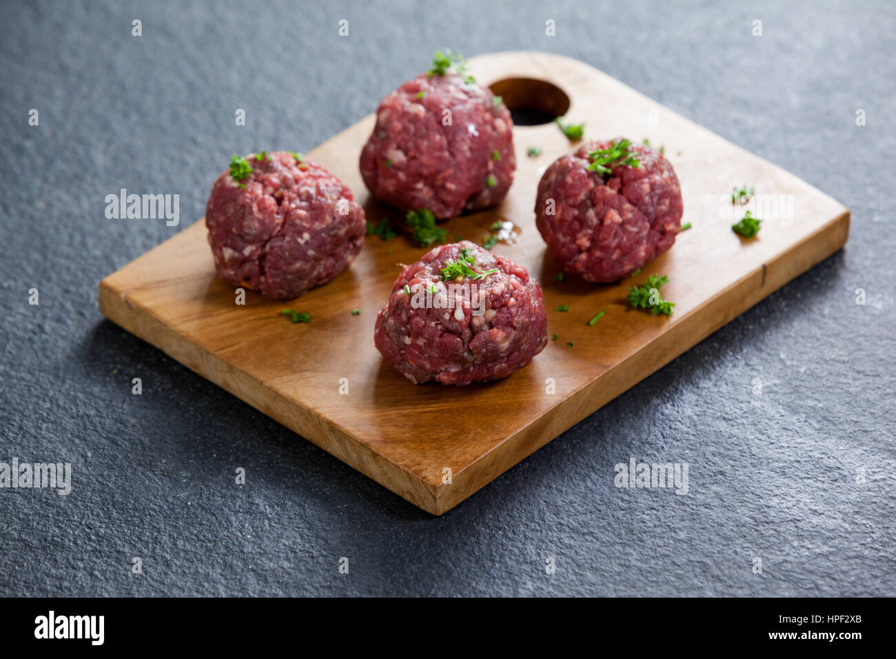 Minced beef garnished with coriander leaves on wooden board against