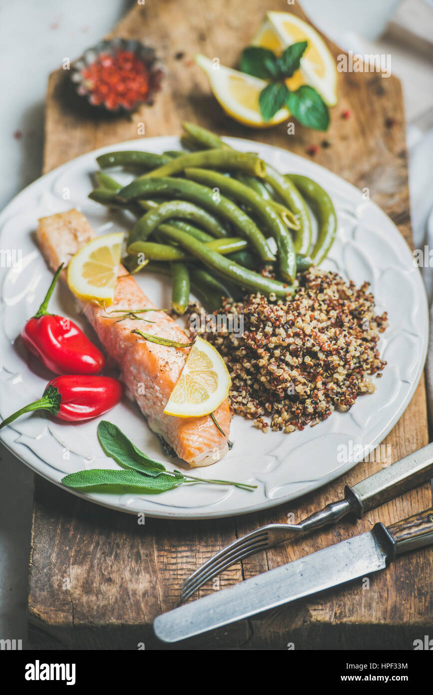 Healthy protein rich dinner plate. Oven roasted salmon fillet with multicolored quinoa, chilli pepper and poached green beans on rustic wooden board o Stock Photo