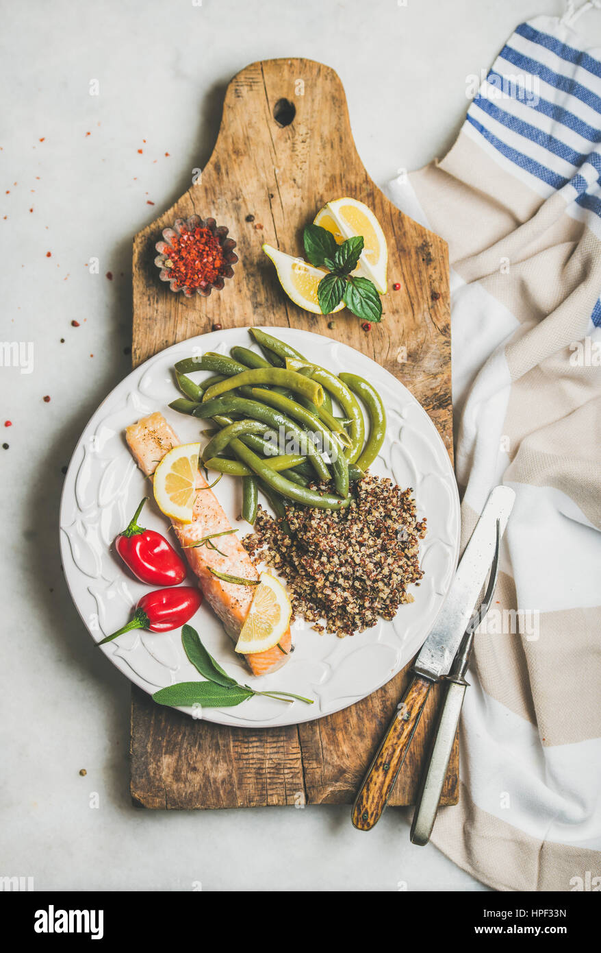Healthy protein rich dinner plate. Oven roasted salmon fillet with multicolored quinoa, chilli pepper and poached green beans on rustic wooden board o Stock Photo