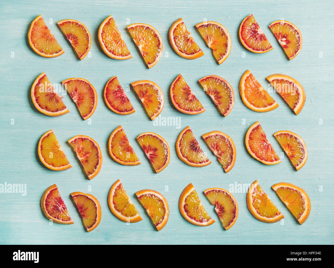 Natural fruit pattern concept. Fresh juicy blood orange slices placed in rows over light blue painted table background, top view Stock Photo