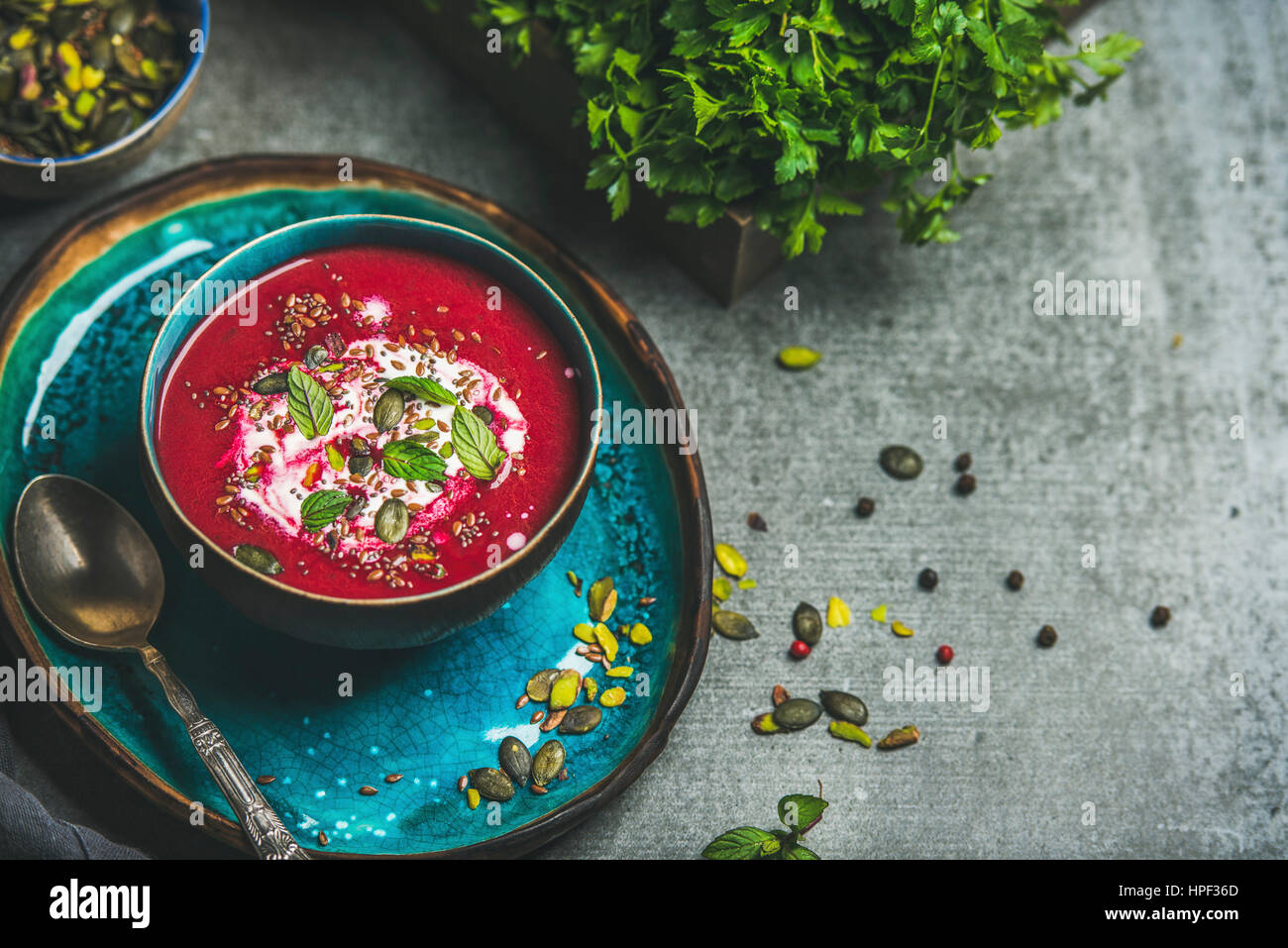 Spring detox beetroot soup with mint, chia, flax and pumpkin seeds on bright blue ceramic plate over grey concrete background, copy space. Dieting, cl Stock Photo