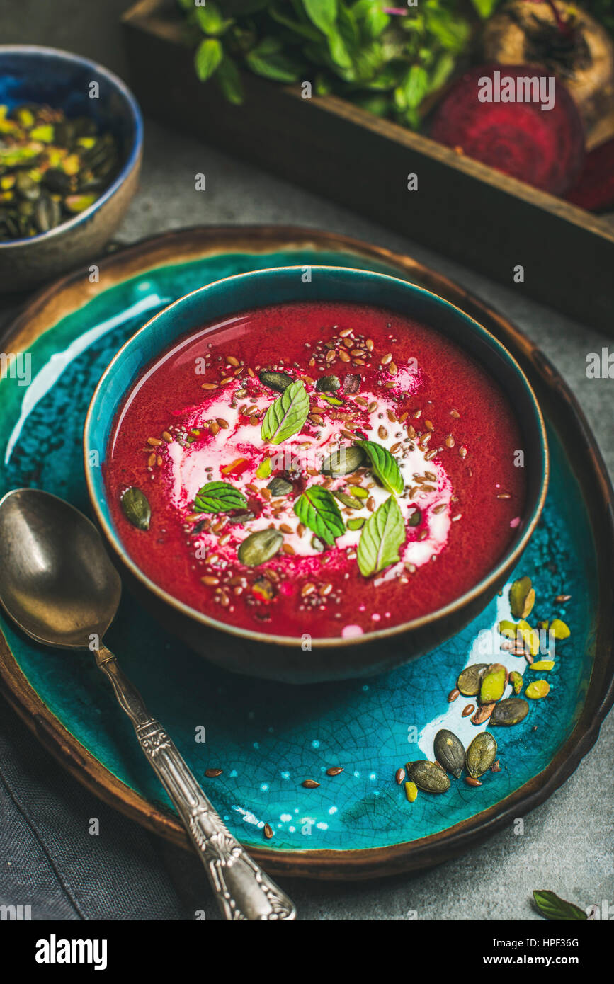 Spring detox red beetroot soup with mint, chia, flax and pumpkin seeds in blue ceramic bowl over grey concrete background. Dieting, clean eating, vega Stock Photo
