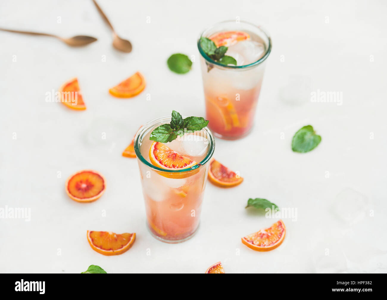 Blood orange fresh summer lemonade with ice and mint in glasses, light grey marble background, selective focus Stock Photo