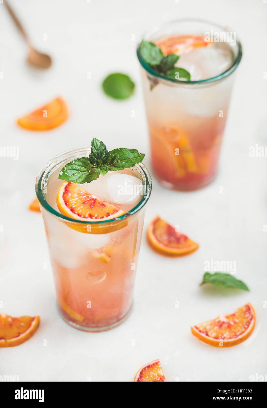 Blood orange fresh summer homemade lemonade with ice and mint in glasses, light grey marble background, selective focus Stock Photo