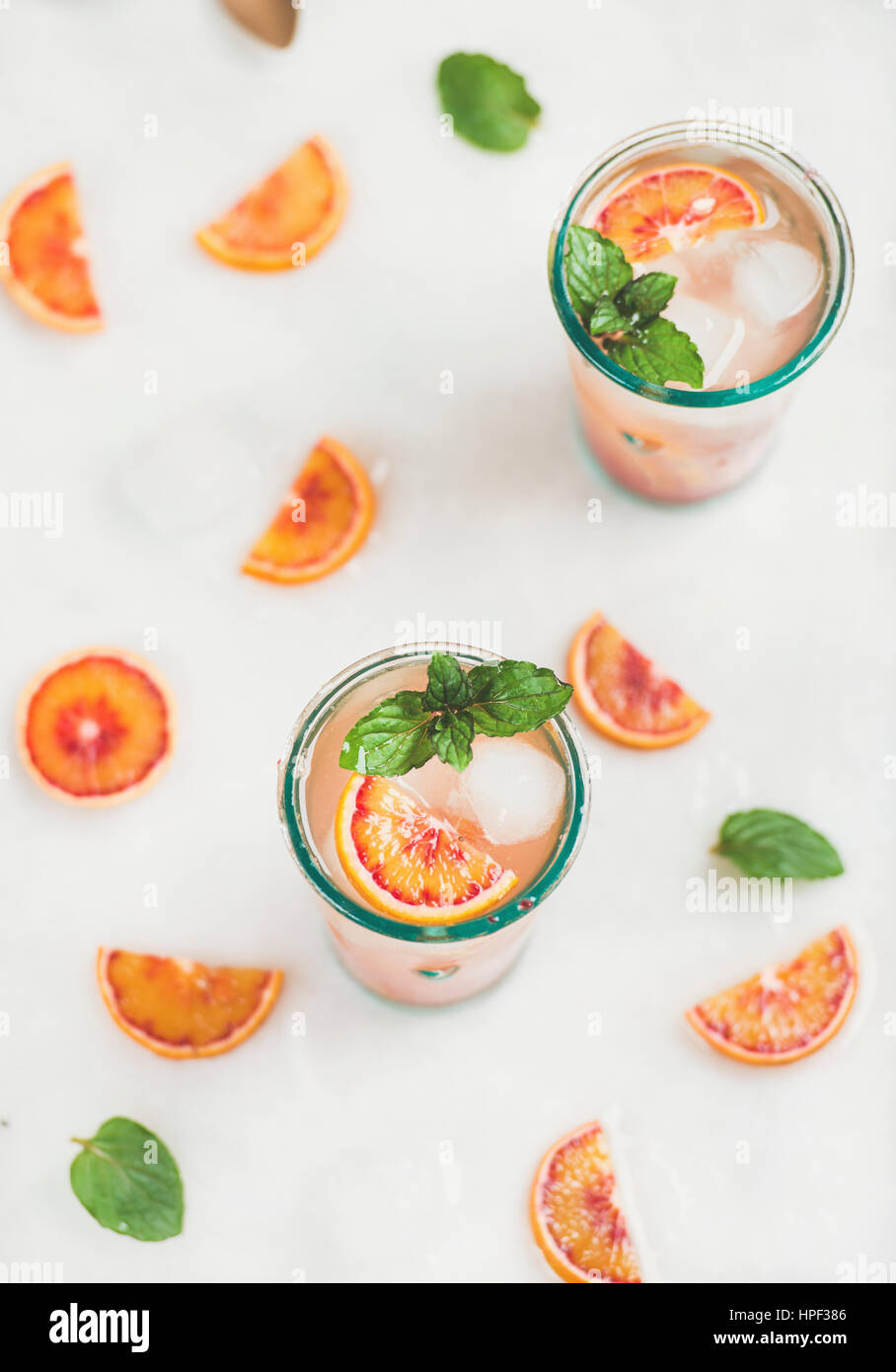 Blood orange fresh summer homemade lemonade with ice and mint in glasses, light grey marble background, top view, selective focus Stock Photo