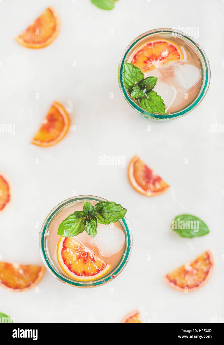 Blood orange fresh summer homemade lemonade with ice and mint in glasses, light grey marble background, top view, selective focus, vertical compositio Stock Photo