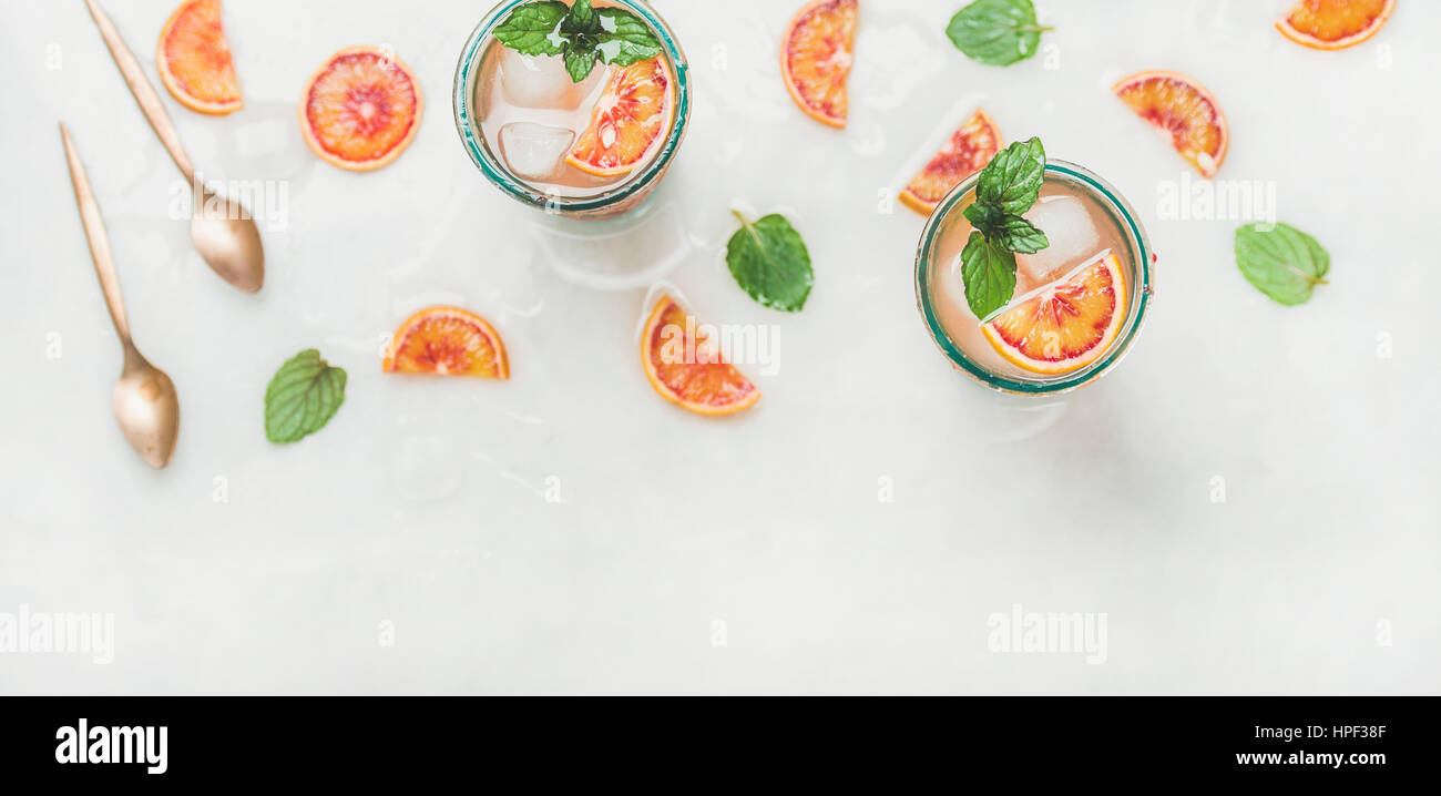 Blood orange fresh summer lemonade with ice and mint in glasses, light grey marble background, selective focus, top view, copy space Stock Photo