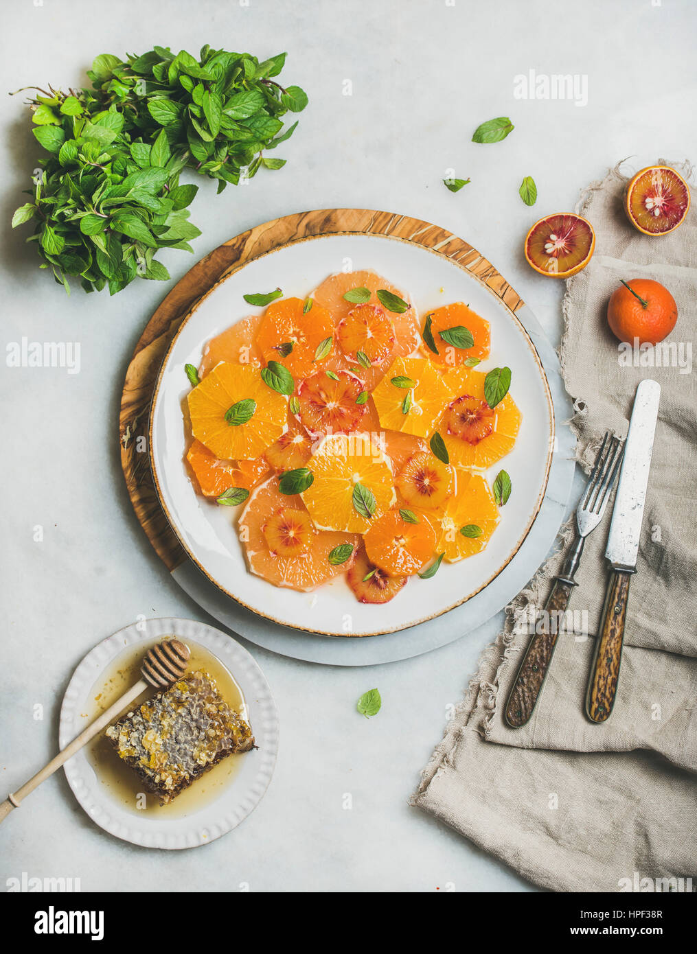 Fresh mixed citrus fruit salad with mint and honey on white ceramic plate over grey background, top view. Vegan, vegetarian, healthy, dieting, detox f Stock Photo